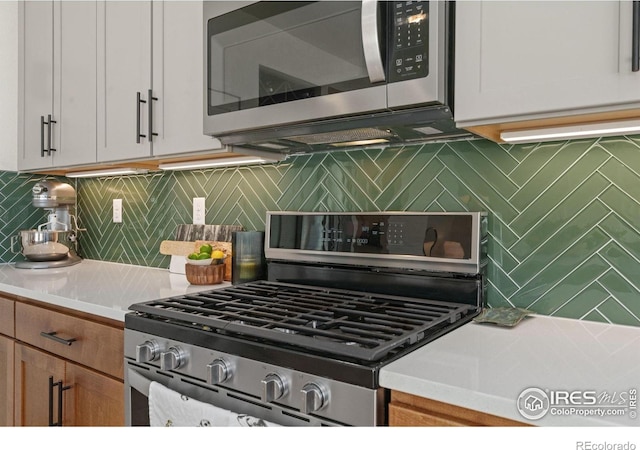 kitchen with stainless steel appliances, backsplash, and white cabinetry