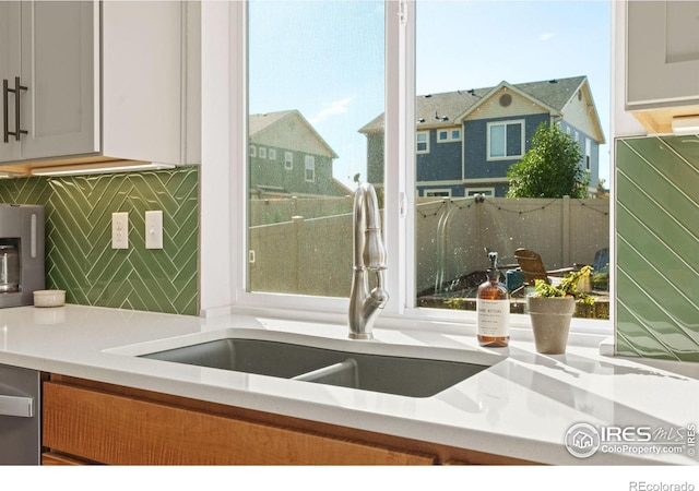 kitchen featuring sink, white cabinetry, dishwasher, and tasteful backsplash