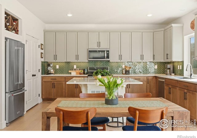 kitchen featuring light hardwood / wood-style flooring, stainless steel appliances, tasteful backsplash, a kitchen bar, and sink