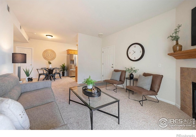 living room with a tiled fireplace and light carpet