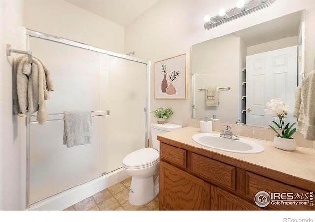 bathroom with toilet, vanity, and a shower with shower door