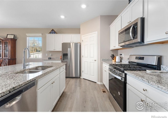 kitchen with stainless steel appliances, white cabinetry, and sink