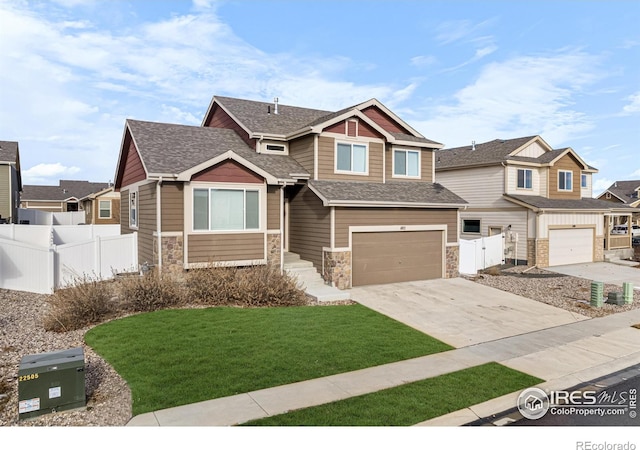 craftsman-style home featuring driveway, a shingled roof, stone siding, fence, and a front lawn