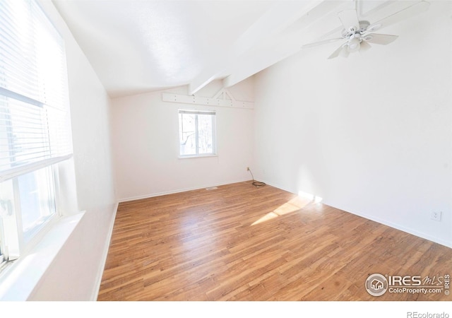 spare room with ceiling fan, lofted ceiling with beams, and light hardwood / wood-style floors