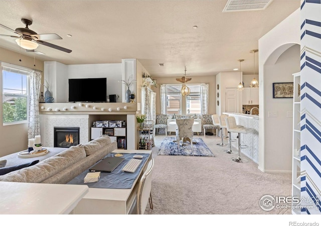 living room with ceiling fan with notable chandelier, a textured ceiling, and carpet floors