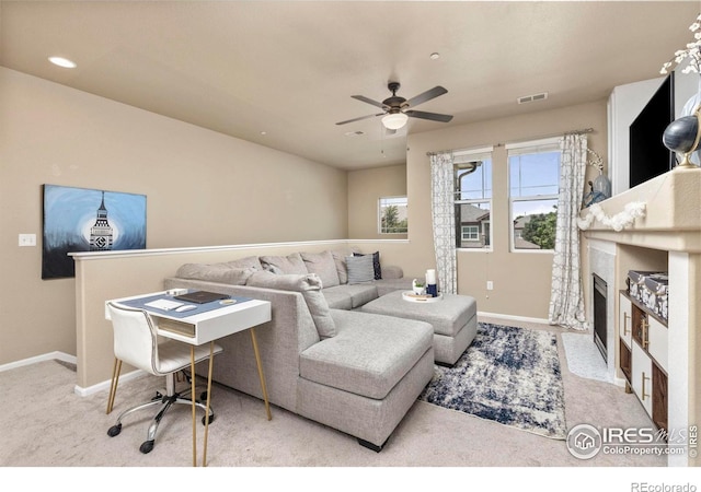 carpeted living room featuring a high end fireplace and ceiling fan