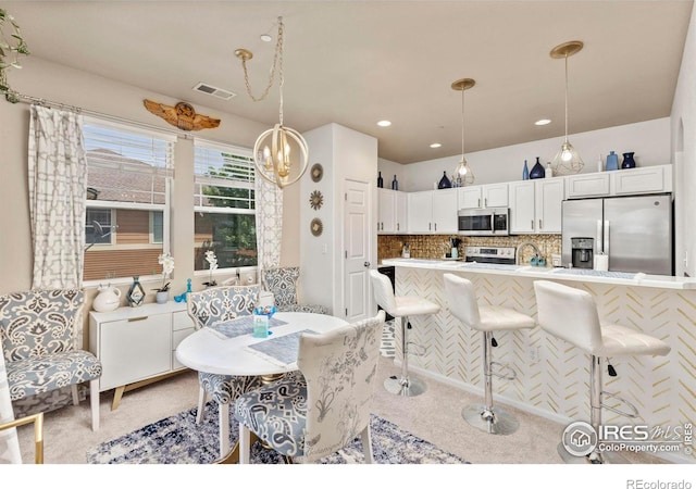 kitchen with appliances with stainless steel finishes, white cabinets, decorative light fixtures, and decorative backsplash