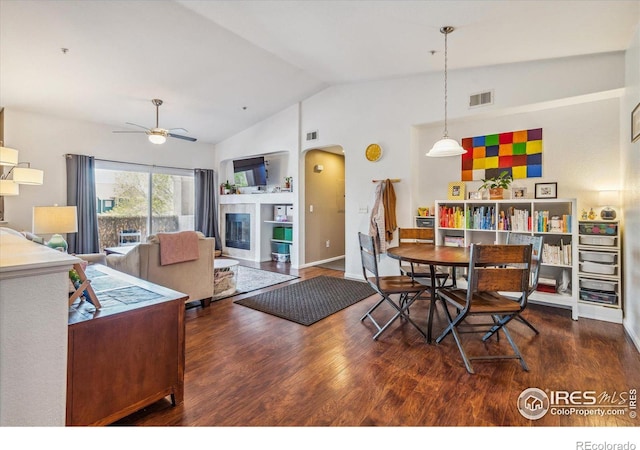 dining area featuring ceiling fan, vaulted ceiling, and dark hardwood / wood-style flooring