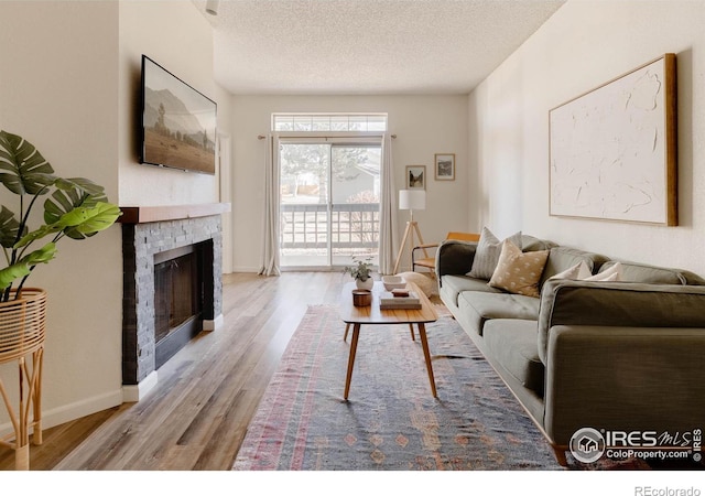 living room with a fireplace, a textured ceiling, and light wood-type flooring