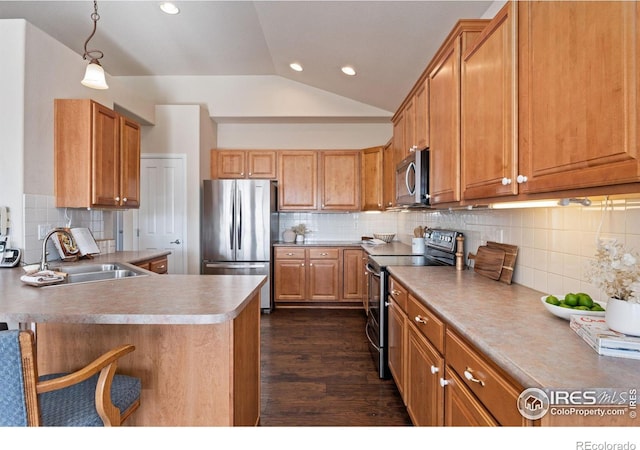 kitchen with vaulted ceiling, appliances with stainless steel finishes, pendant lighting, sink, and tasteful backsplash