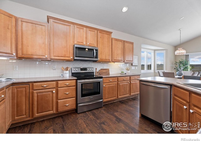 kitchen featuring stainless steel appliances, lofted ceiling, tasteful backsplash, hanging light fixtures, and dark wood-type flooring