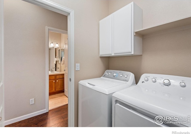 laundry room featuring sink, washing machine and clothes dryer, cabinets, and dark hardwood / wood-style floors