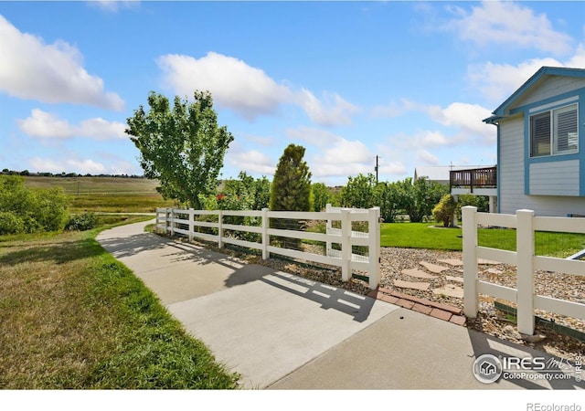 view of gate featuring a rural view, a patio area, and a lawn