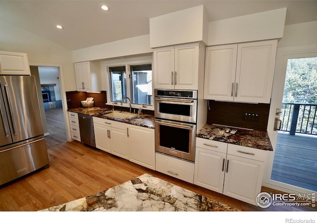 kitchen featuring tasteful backsplash, white cabinetry, appliances with stainless steel finishes, and sink