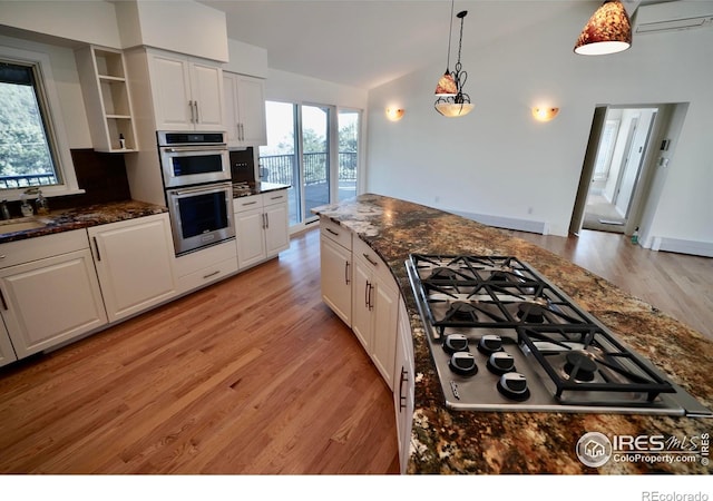 kitchen featuring pendant lighting, stainless steel appliances, dark stone countertops, and white cabinets