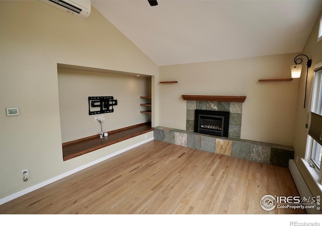 unfurnished living room featuring a wall mounted AC, vaulted ceiling, baseboard heating, a fireplace, and hardwood / wood-style floors