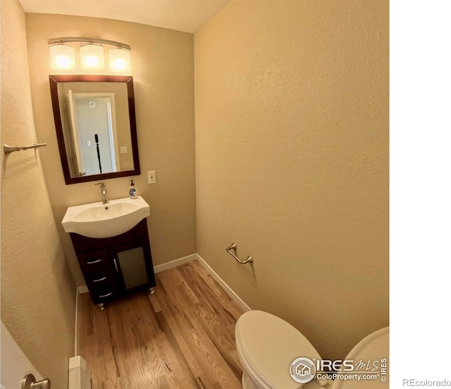 bathroom featuring wood-type flooring, vanity, and toilet