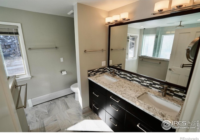 bathroom with vanity, decorative backsplash, a wealth of natural light, and toilet