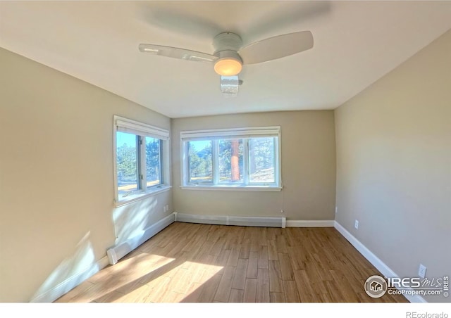 spare room with a baseboard radiator, light hardwood / wood-style floors, and ceiling fan