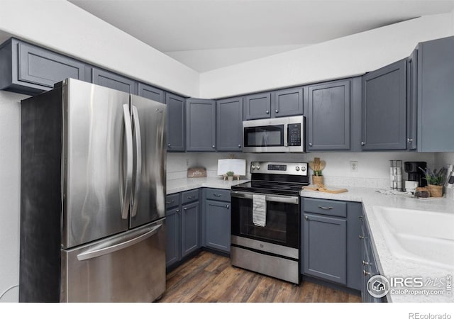 kitchen featuring dark wood-type flooring, stainless steel appliances, gray cabinets, and sink