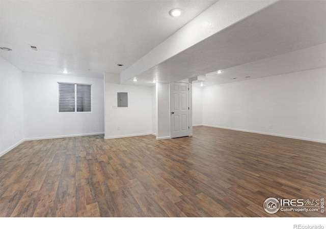 basement with dark wood-type flooring and electric panel