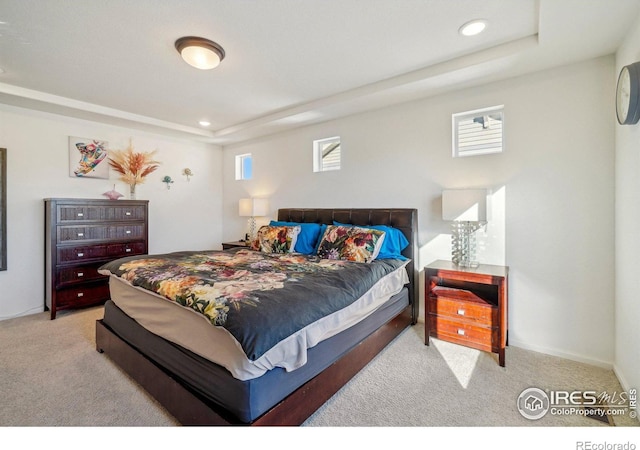 carpeted bedroom with a tray ceiling