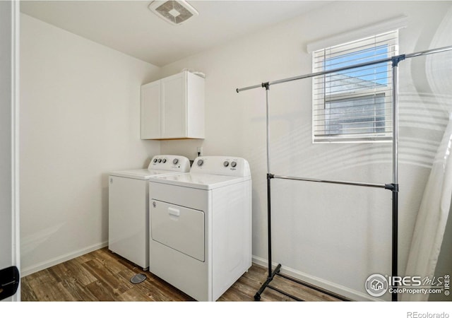 laundry room with visible vents, wood finished floors, washing machine and dryer, baseboards, and cabinet space