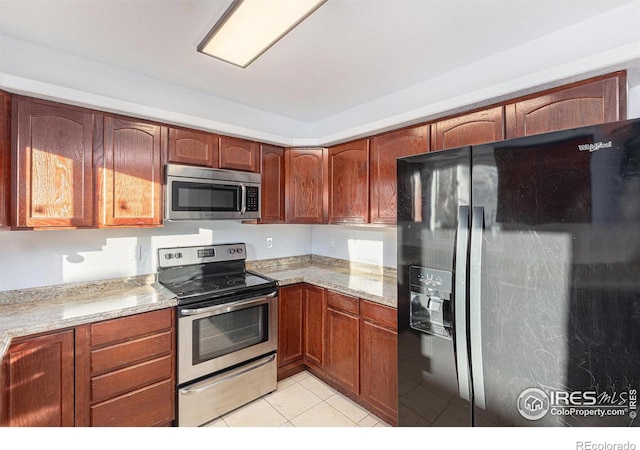 kitchen featuring light tile patterned floors, light stone counters, and stainless steel appliances