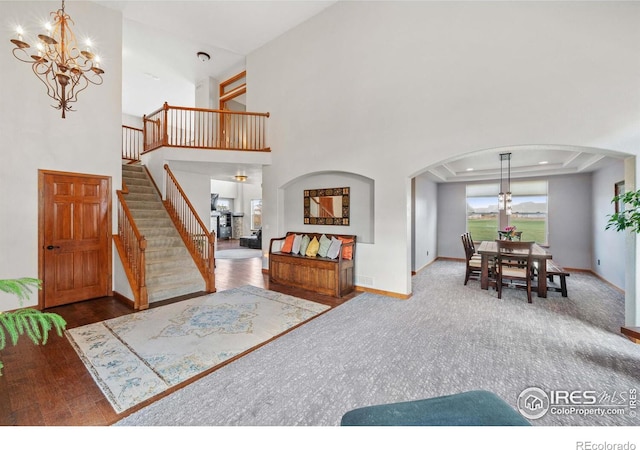 living room featuring wood-type flooring, a raised ceiling, and a chandelier