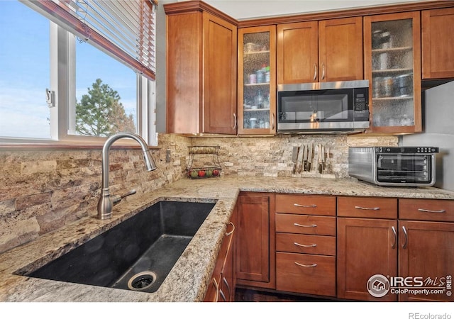 kitchen with light stone counters, sink, and decorative backsplash