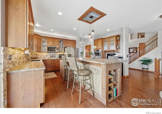 kitchen with hardwood / wood-style floors, pendant lighting, a center island, decorative backsplash, and appliances with stainless steel finishes