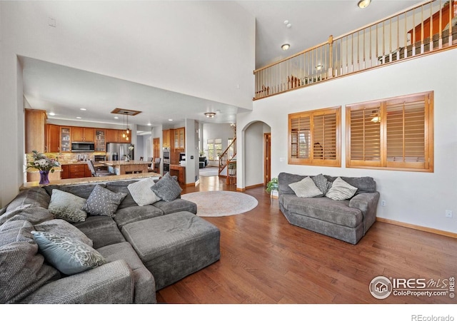 living room featuring a towering ceiling, decorative columns, and light hardwood / wood-style flooring