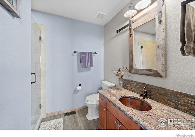 bathroom with hardwood / wood-style floors, toilet, vanity, and an enclosed shower