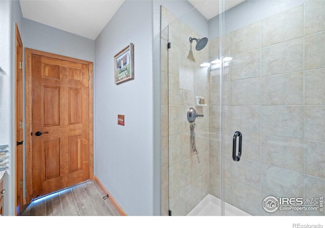 bathroom featuring wood-type flooring and an enclosed shower