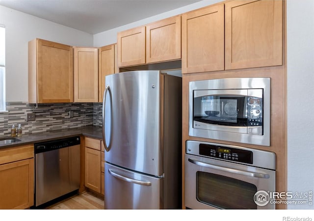 kitchen with light brown cabinets, stainless steel appliances, tasteful backsplash, and sink