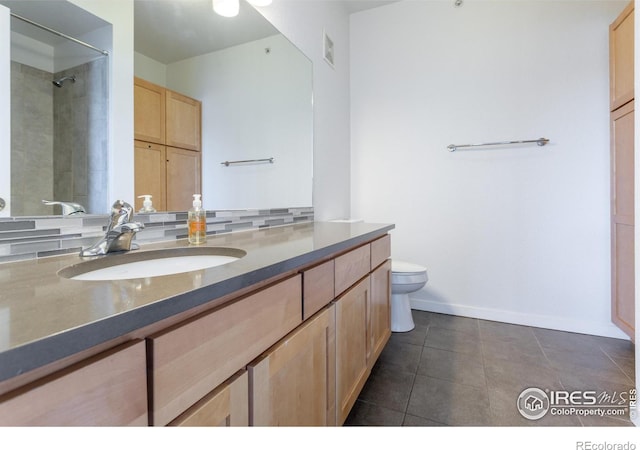 bathroom featuring toilet, vanity, tile patterned floors, and tiled shower