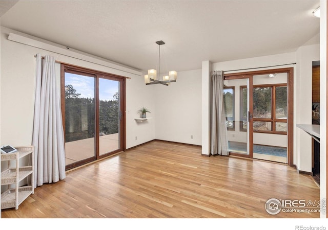 unfurnished dining area featuring a chandelier and light hardwood / wood-style floors