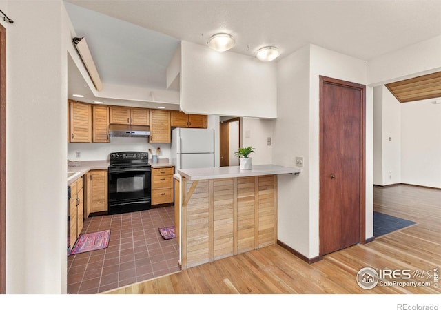 kitchen featuring white refrigerator, black electric range oven, light hardwood / wood-style floors, and kitchen peninsula