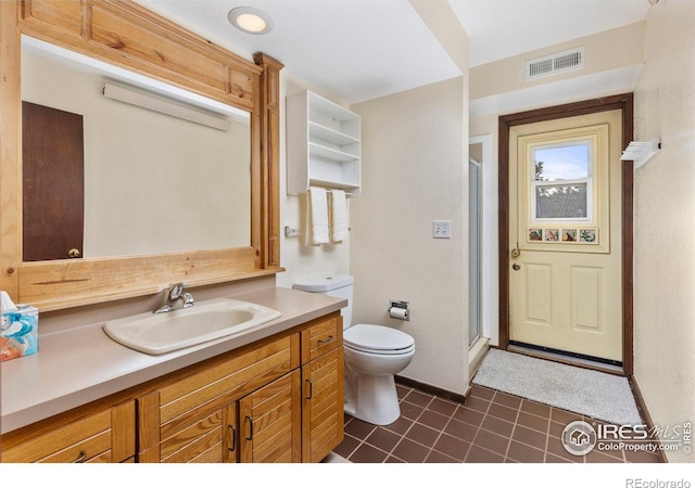 bathroom with an enclosed shower, vanity, toilet, and tile patterned flooring