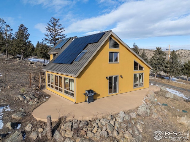 rear view of house with solar panels and a sunroom