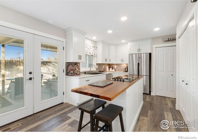 kitchen featuring decorative backsplash, white cabinetry, stainless steel fridge, and french doors