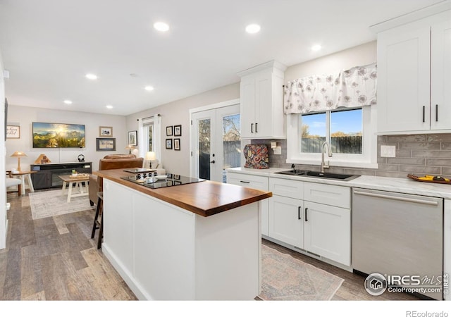 kitchen featuring stainless steel dishwasher, sink, black electric stovetop, and white cabinetry