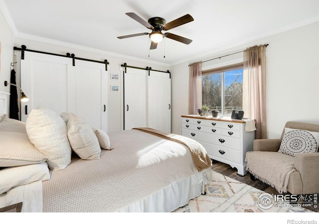 bedroom featuring ceiling fan, wood-type flooring, crown molding, and a barn door