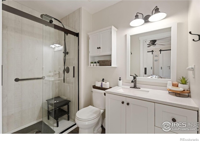 bathroom featuring toilet, ceiling fan, a shower with door, and vanity