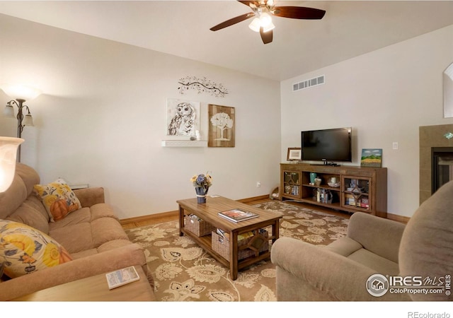 living room featuring ceiling fan and a tile fireplace