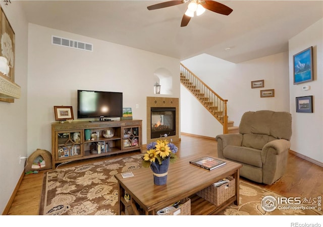 living room with ceiling fan, light hardwood / wood-style flooring, and a fireplace