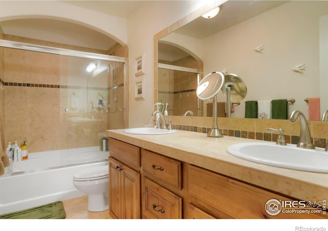 full bathroom featuring decorative backsplash, shower / bath combination with glass door, vanity, and toilet