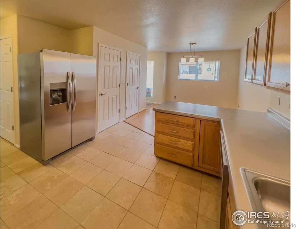 kitchen with sink, hanging light fixtures, light tile patterned flooring, stainless steel fridge with ice dispenser, and kitchen peninsula