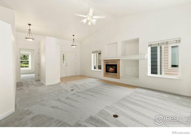 unfurnished living room featuring high vaulted ceiling, light colored carpet, ceiling fan, and a tile fireplace