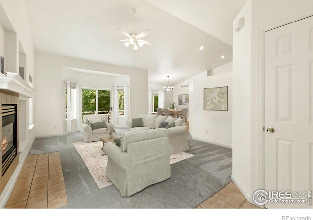 tiled living room featuring vaulted ceiling and ceiling fan with notable chandelier